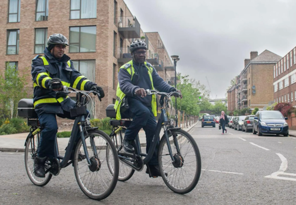 two parking officers riding an e-bike in their working uniform