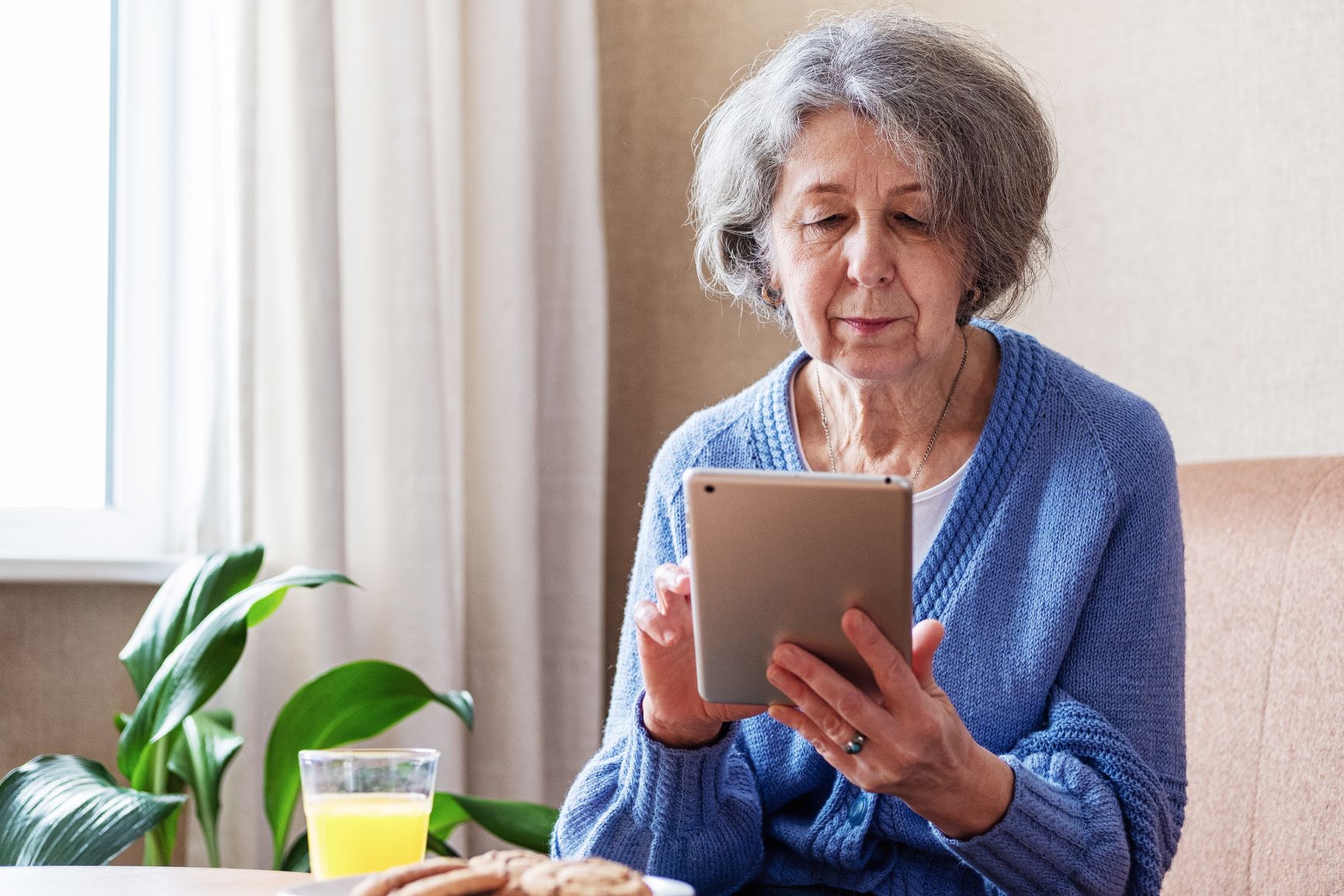 An elderly woman uses a tablet to view content on social networks