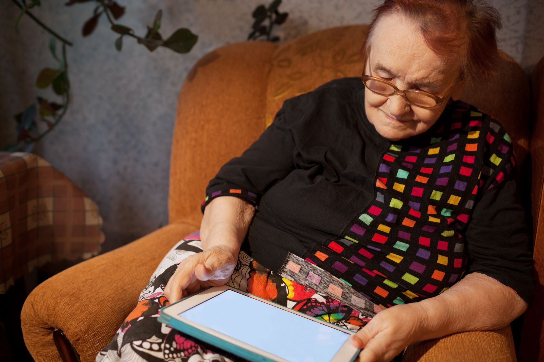 elderly-lady-sitting-in-an-chair-using-a-tablet-XCJWP6U