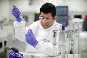 lab tech putting pink liquid in a test tube